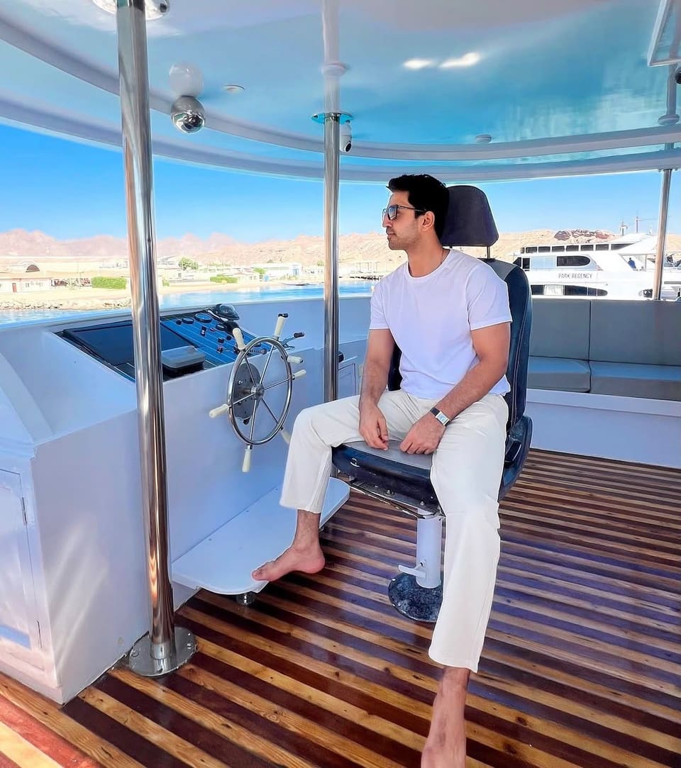 Malik Hamza Javed sitting at the helm of a boat in a harbour