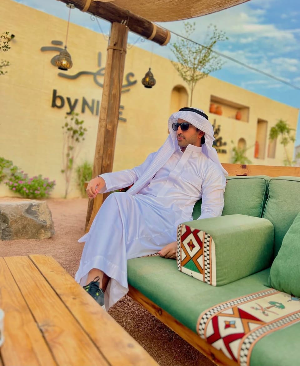 Malik Hamza Javed wearing a white thobe and shemagh in a courtyard café